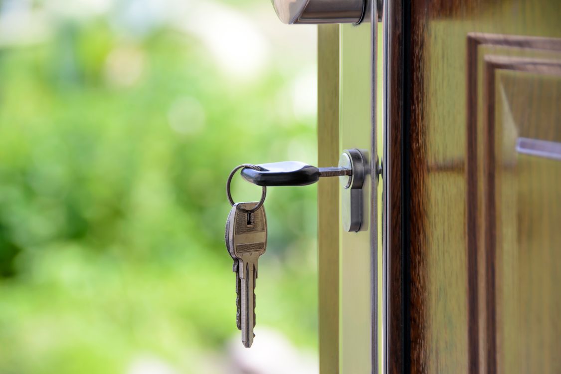 A close-up of a hand holding a set of house keys with the iconic Atlanta city skyline visible in the soft-focus background, representing the Atlanta real estate market.