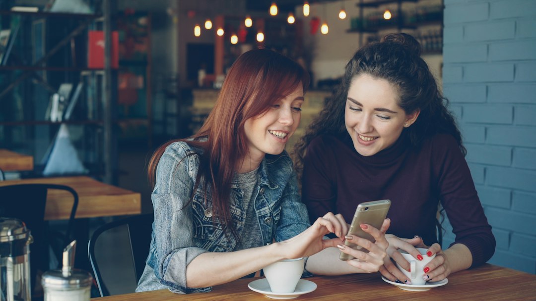 A first-person view of a hand holding a smartphone displaying a map application, with the route leading to a cozy, modern coffee shop in the background.